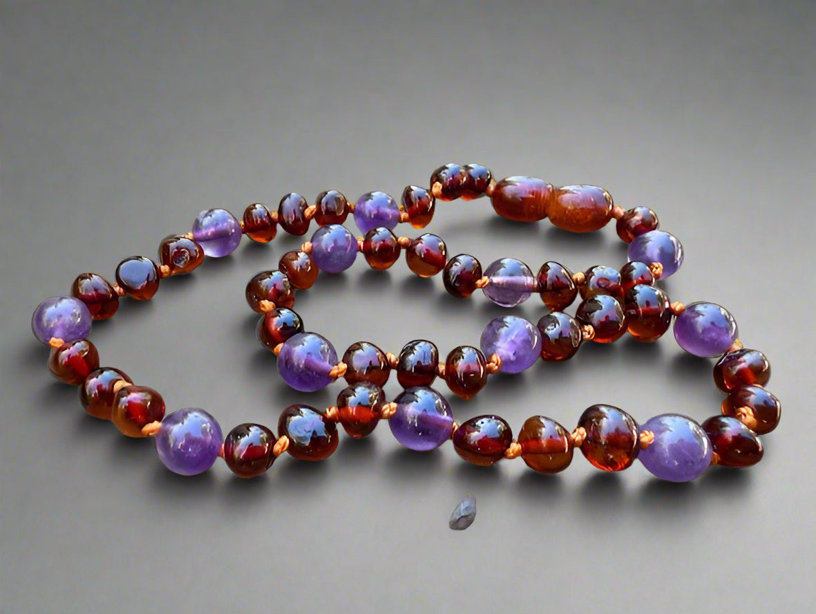 Necklace with purple and amber beads on a wooden surface