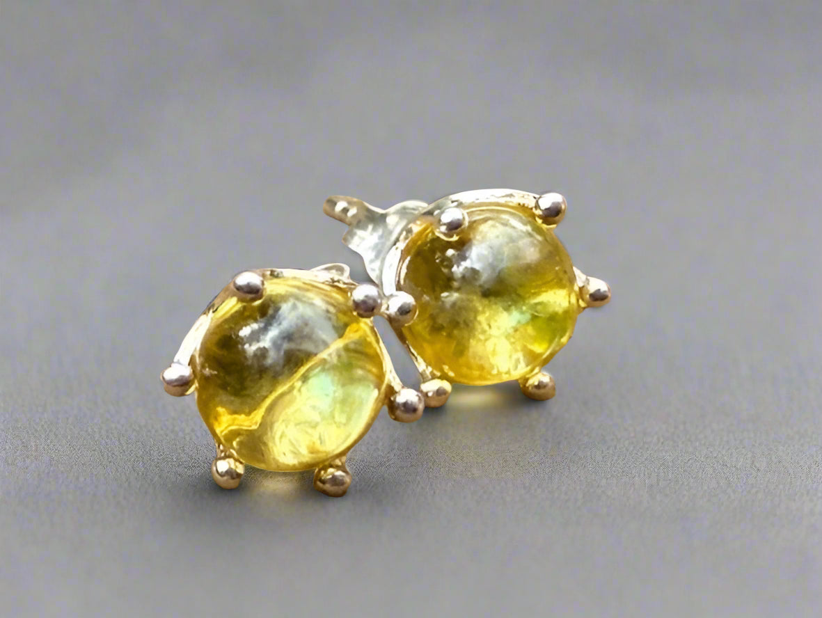 Pair of yellow gemstone stud earrings on a wooden surface