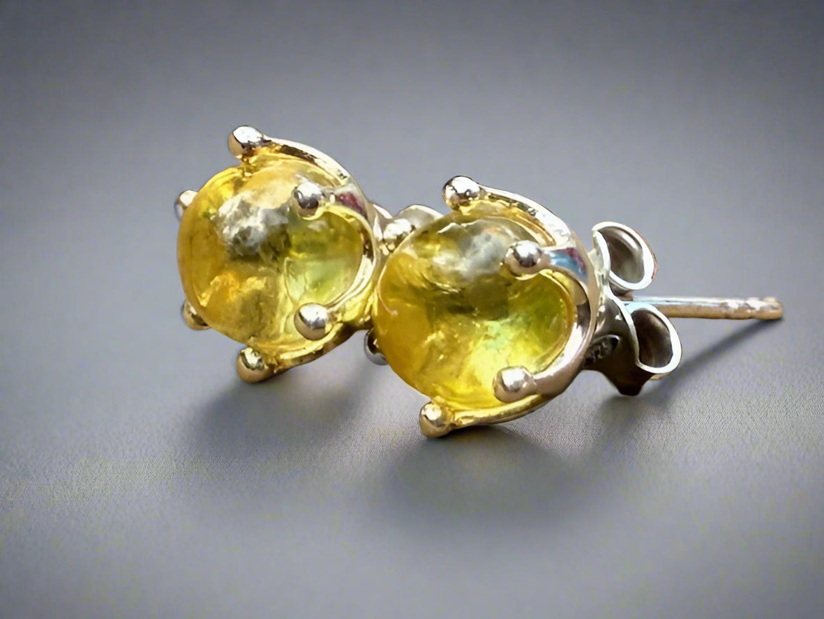Pair of yellow gemstone stud earrings on a wooden surface