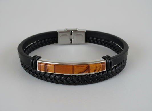 Black braided leather bracelet with a silver clasp on a light surface.