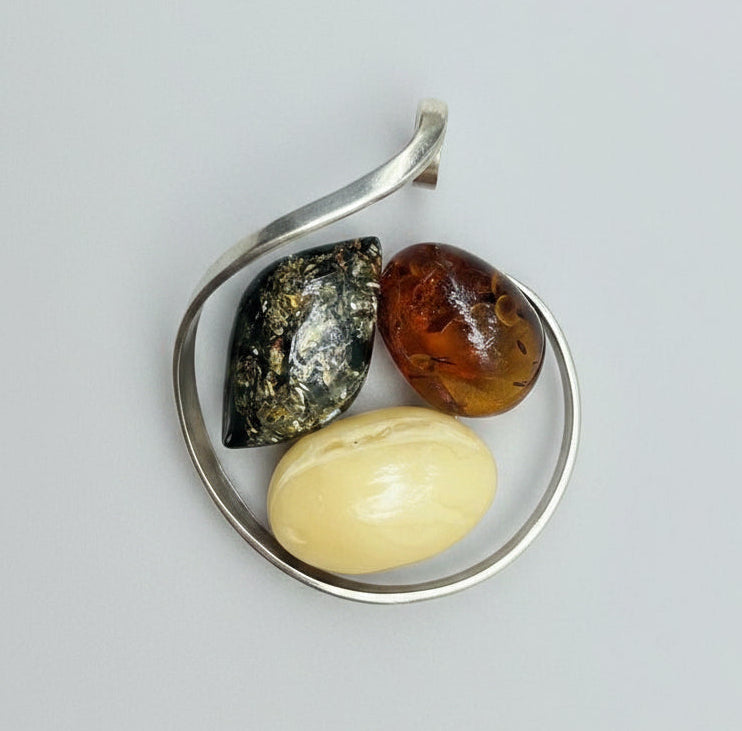 Three stones of different colors in a metal container on a textured stone surface