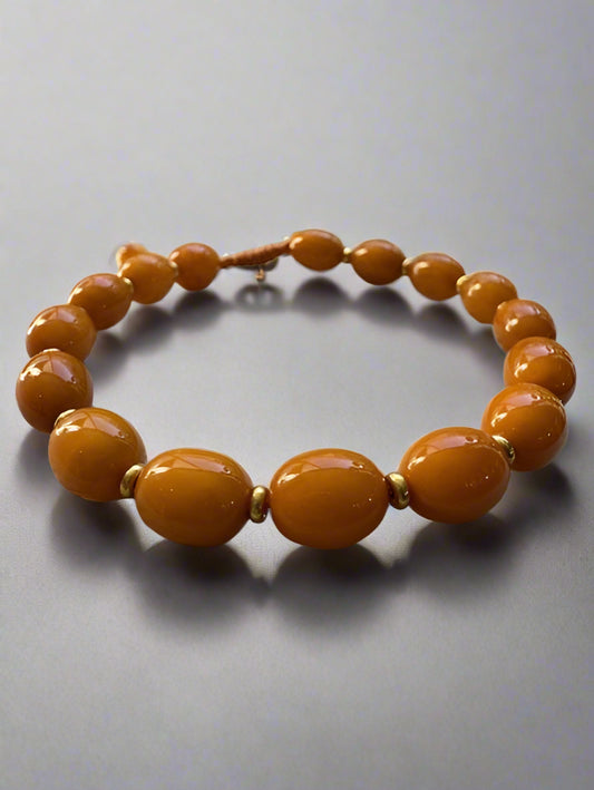 Beige beaded bracelet on a textured surface with a blurred natural background