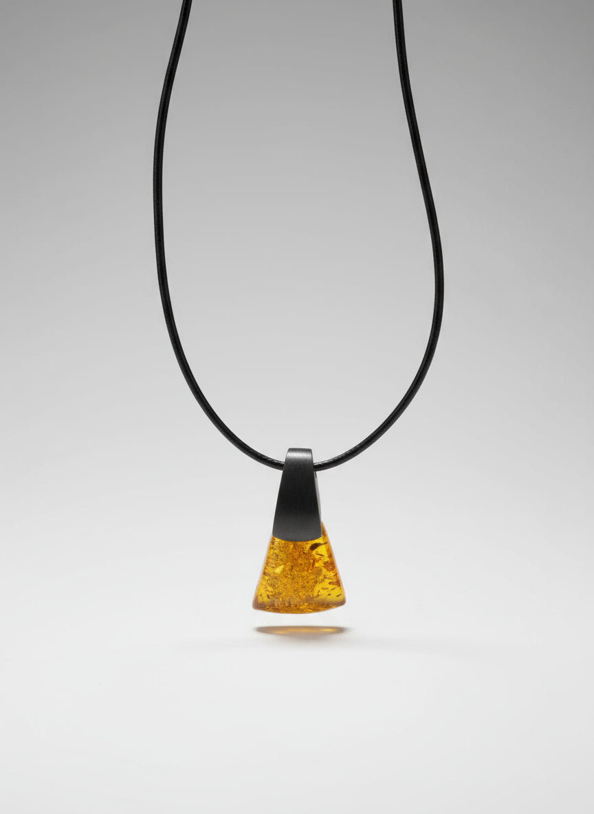 Amber-colored pendant on a black cord against a wooden background