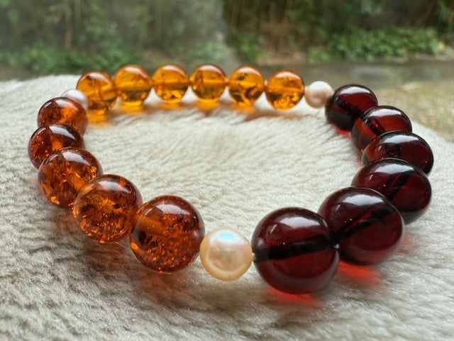 Beaded bracelet with amber and red beads on a textured surface