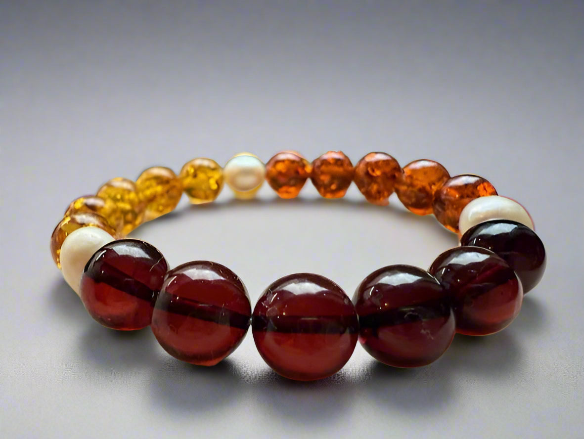 Beaded bracelet with amber and red beads on a textured surface