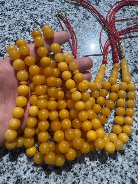 Yellow beaded necklace held by a hand on a speckled surface