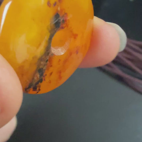 Round amber pendant on a string against a textured beige background video 