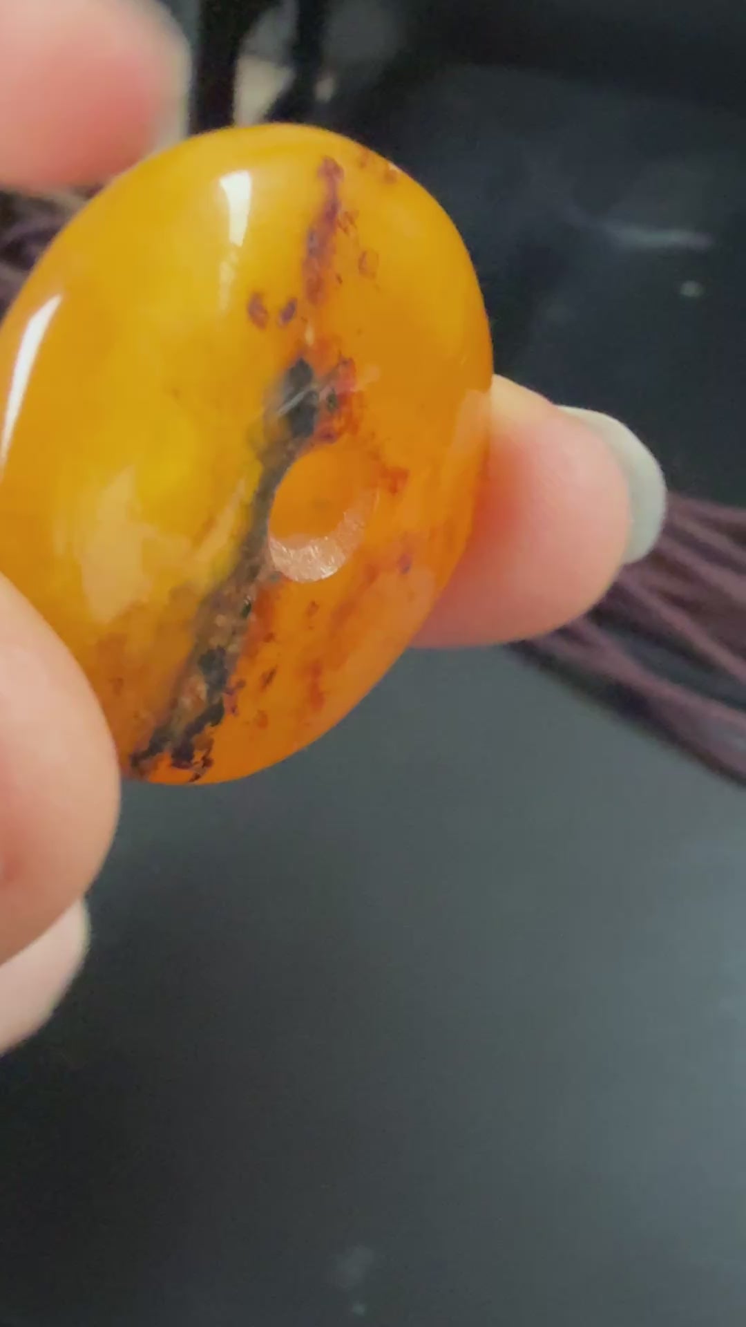 Round amber pendant on a string against a textured beige background video 