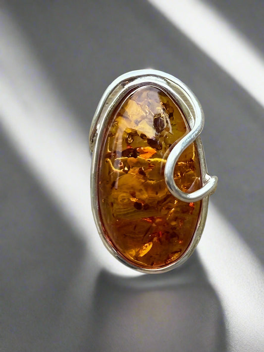 Silver ring with a large amber stone on a gray background