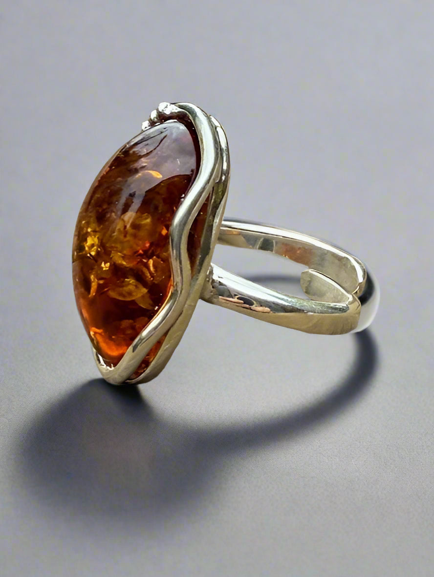 Silver ring with a large amber stone on a wooden surface