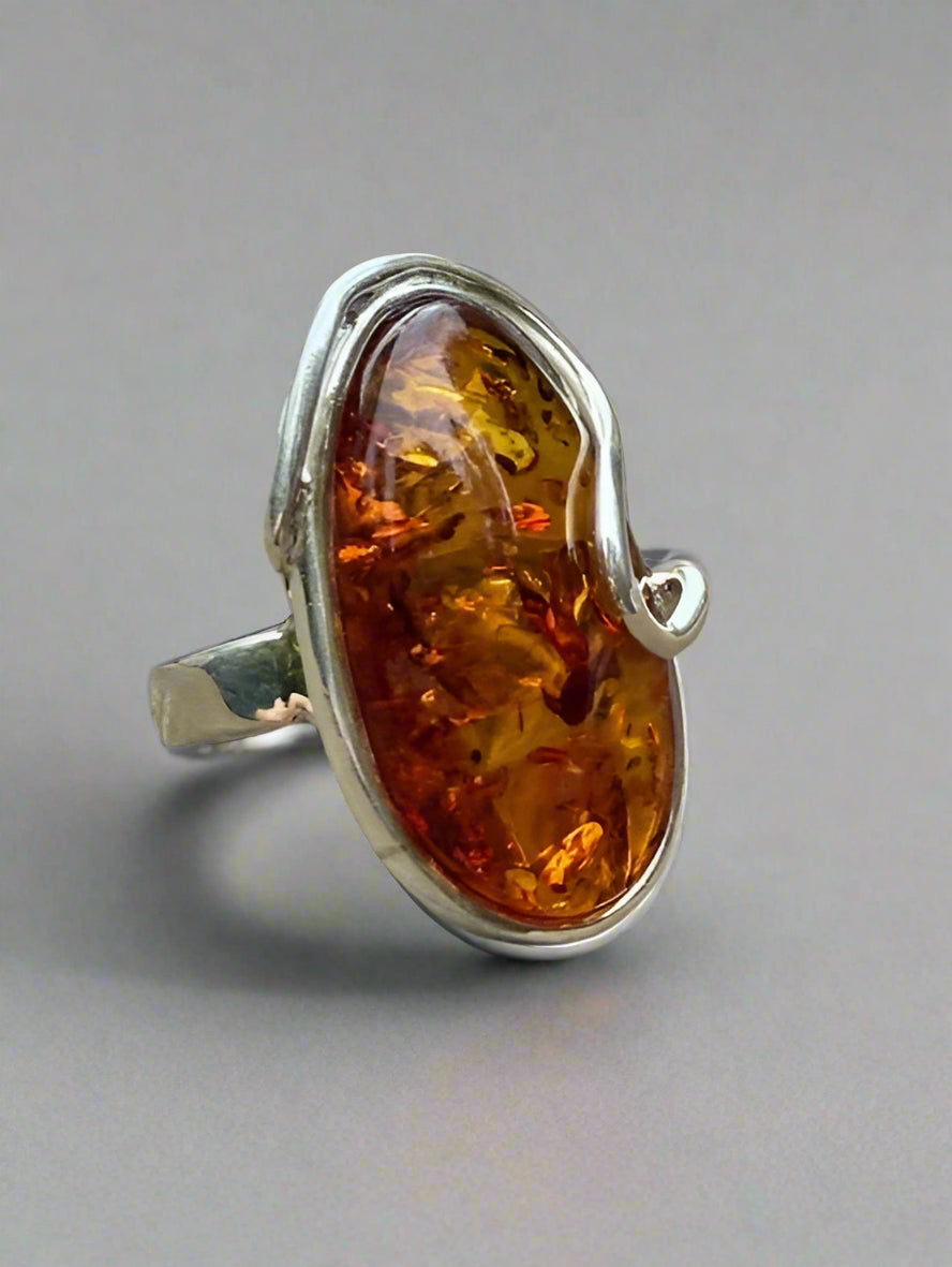 Silver ring with amber stone on a wooden surface