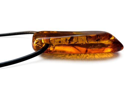 Amber-colored pill on a reflective surface with a dark background